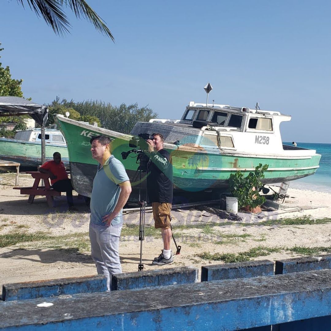 Two men recording on the beach in Barbados.